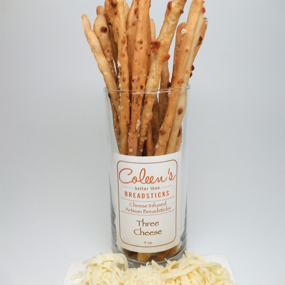 Coleen's three cheese breadsticks in a glass container on a plate with shredded cheese