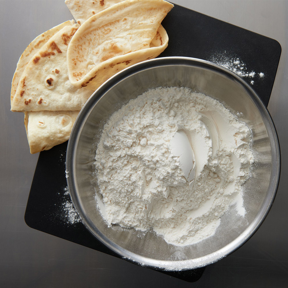 Gold Medal all-purpose flour in a mixing bowl next to pita bread