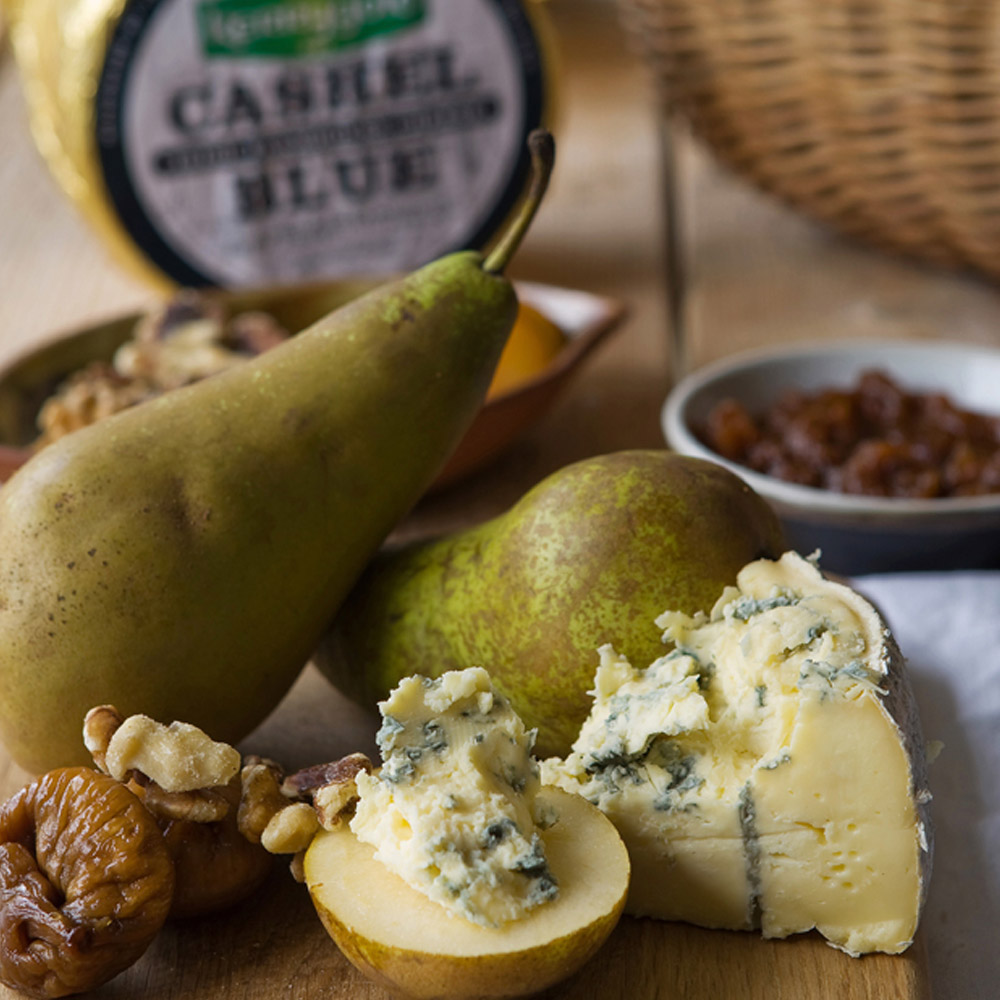 Kerrygold Cashel blue cheese on a cutting board with fresh pears