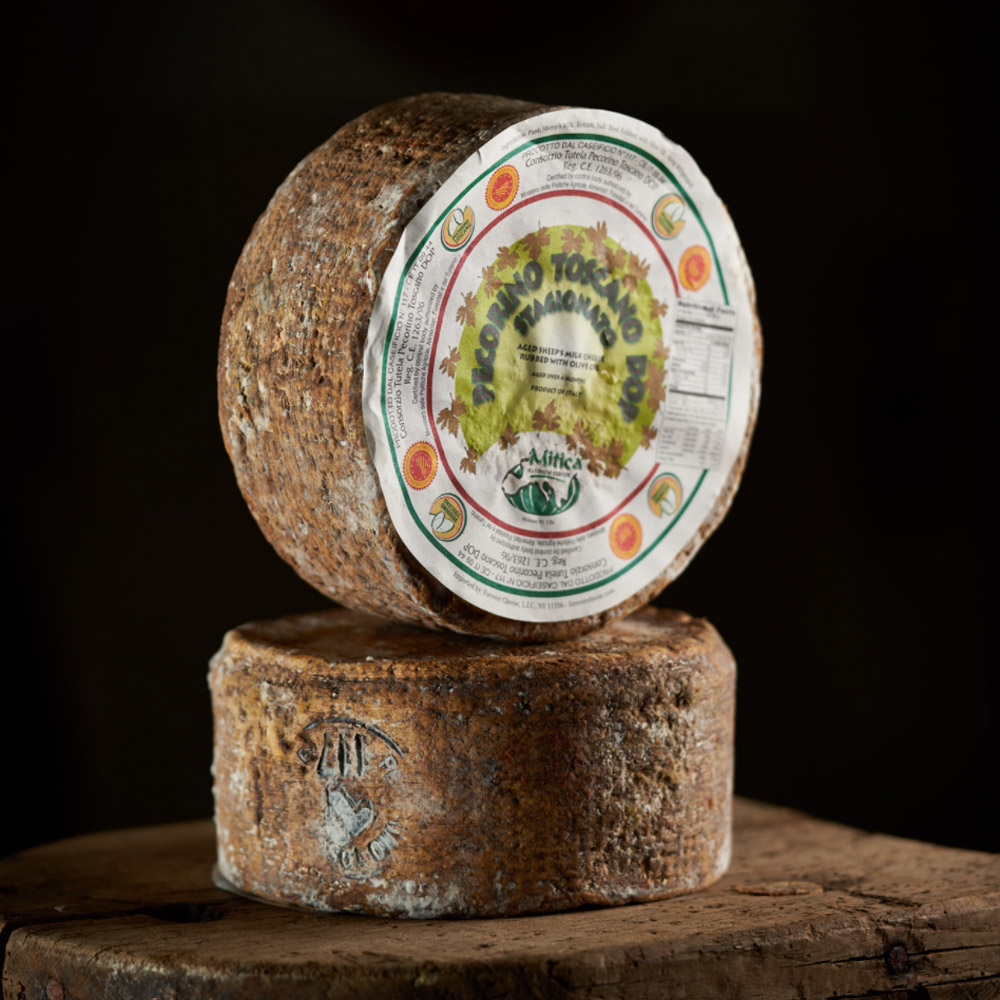 Two stacked wheels of Mitica aged pecorino toscano DOP cheese