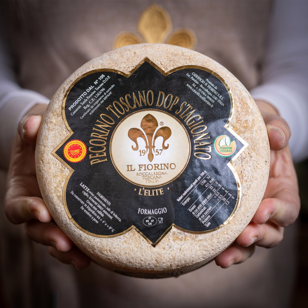 A wheel of Il Fiorino Pecorino Toscano Stagionato cheese in a persons hands