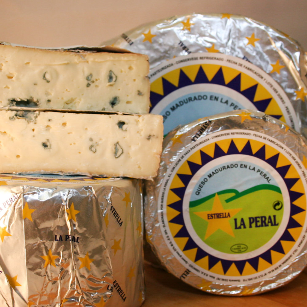 Wheel of La Peral blue cheese next to a cut wheel of cheese