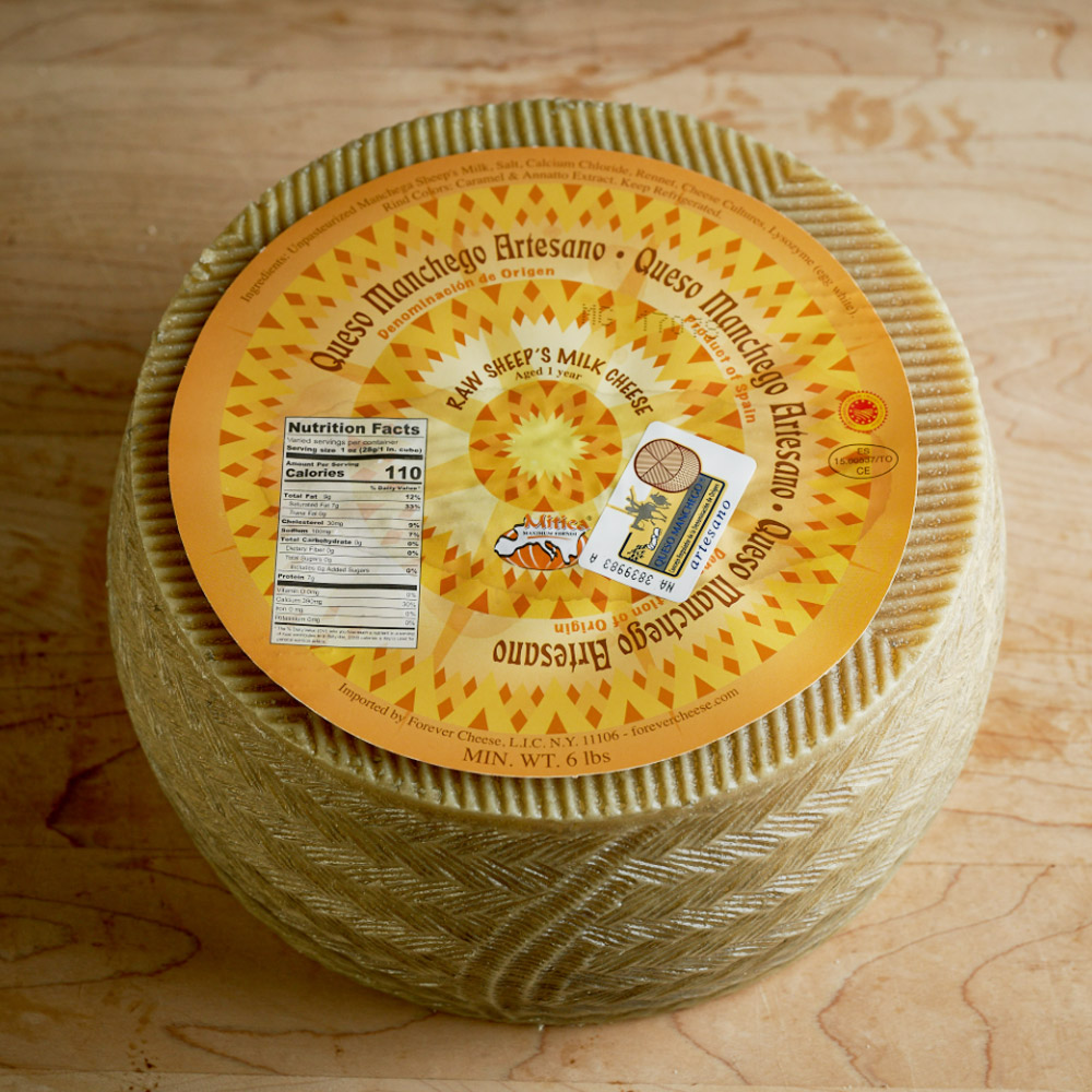 Wheel of Mitica 1 Year DOP Manchego cheese on a wood surface