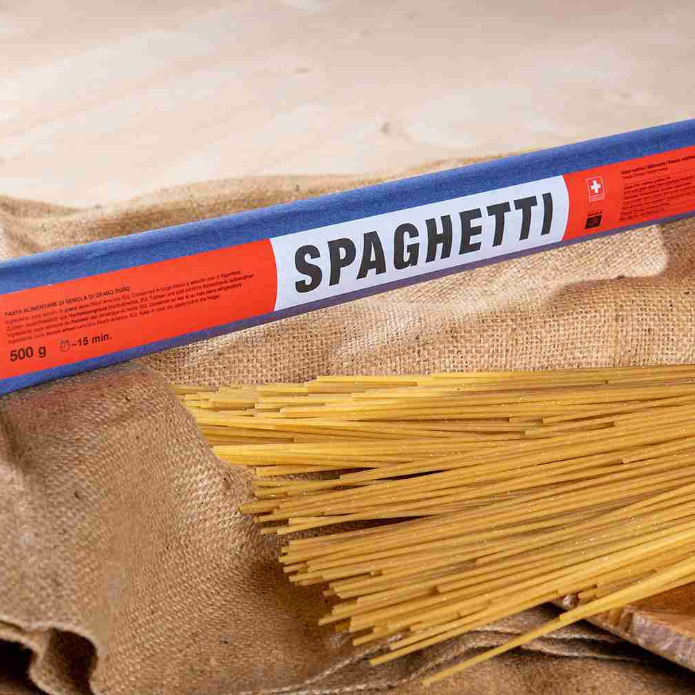 A package of Poschiavo Spaghetti pasta on top of a burlap sack next to pasta