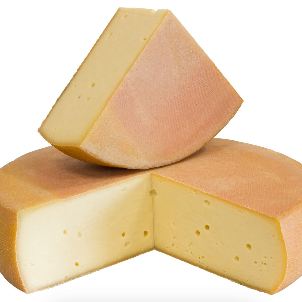 A wheel of Alpencheddar with a wedge cut out and stacked on top