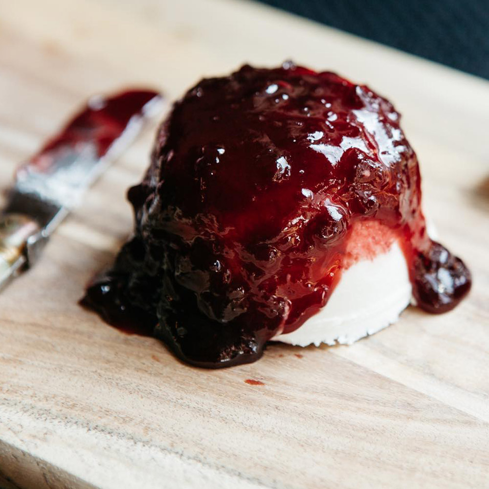 Mackenzie Creamery Sour Cherry Bourbon Chèvre on a wood board next to a cheese knife