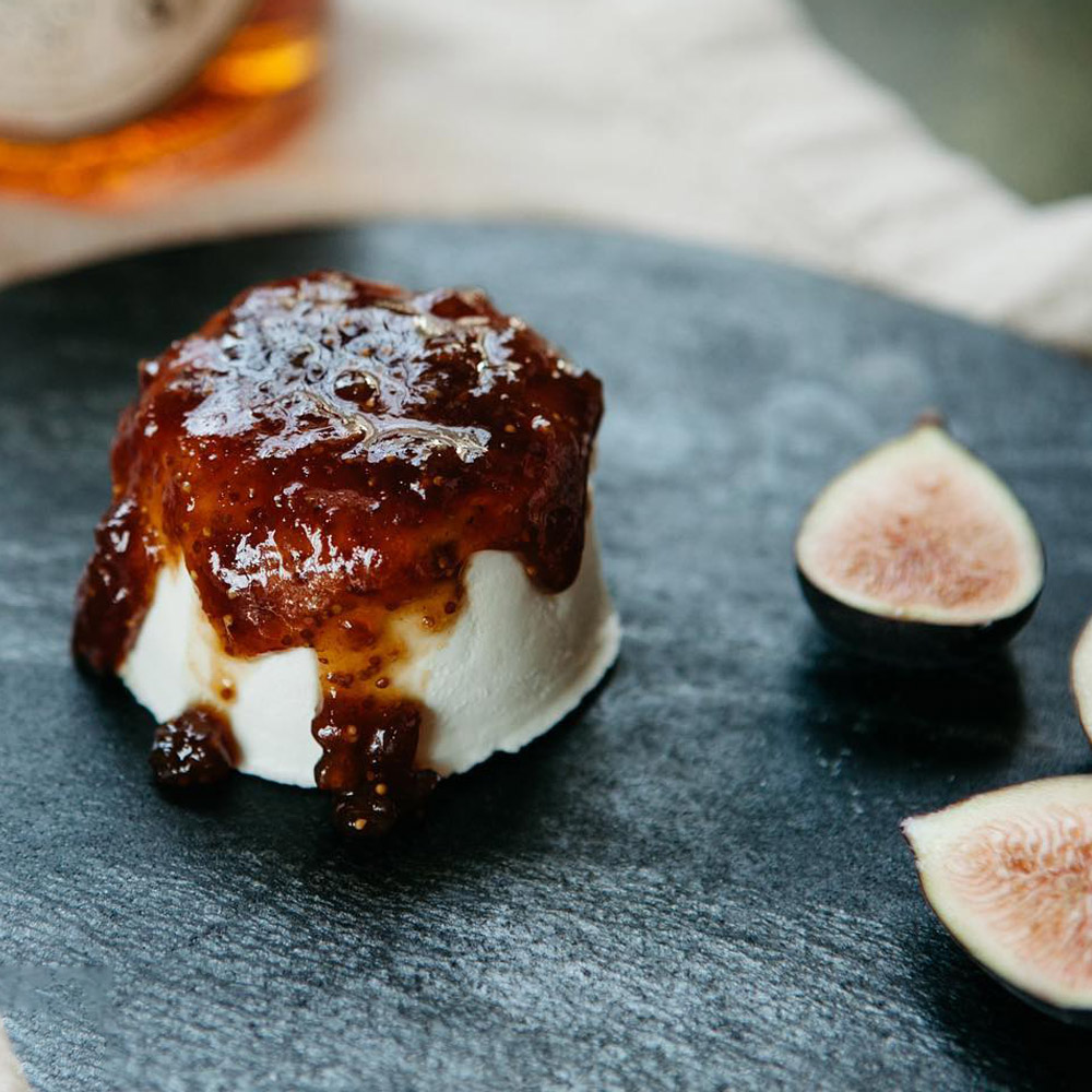 Mackenzie Creamery Cognac Fig Chèvre on a board next to two fig halves