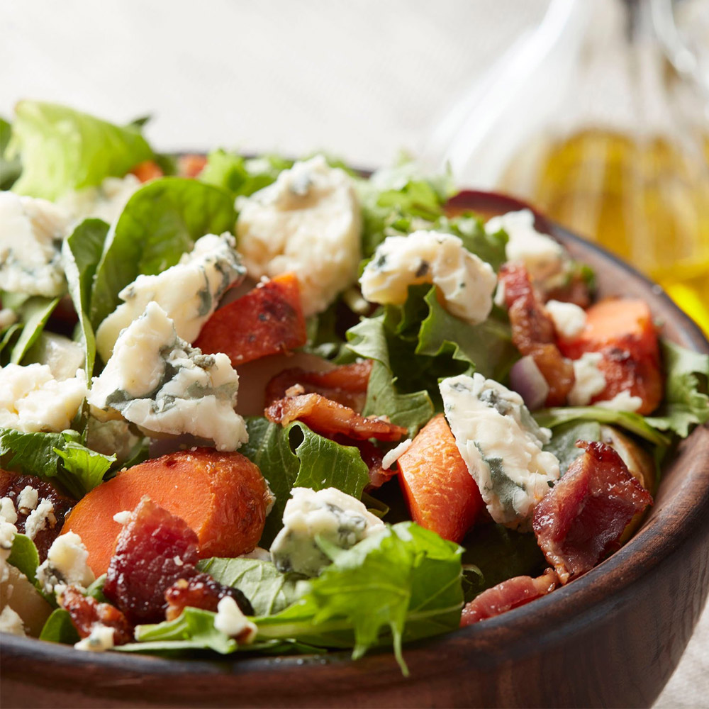 A close-up of a salad topped with gorgonzola cheese crumbles