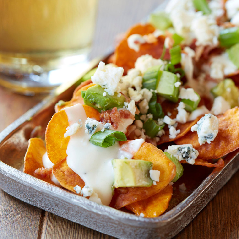 A plate of buffalo nachos topped with blue cheese crumbles