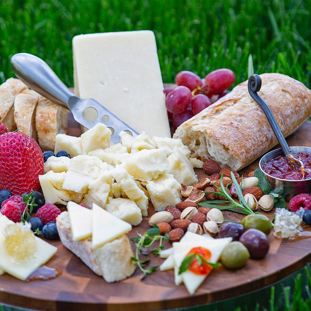 A cheese board with white cheddar and other snacks