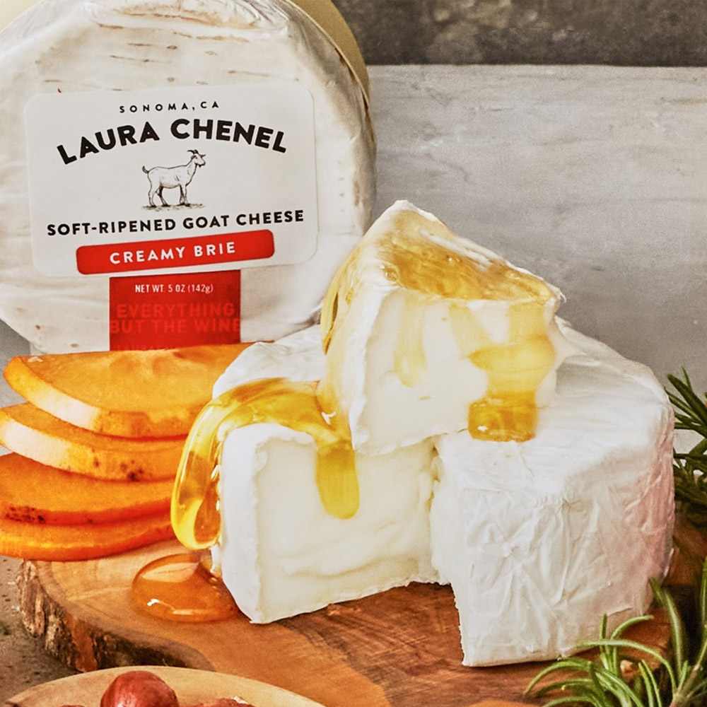 Laura Chenel brie in the packaging next to an unwrapped wheel of brie drizzled with honey