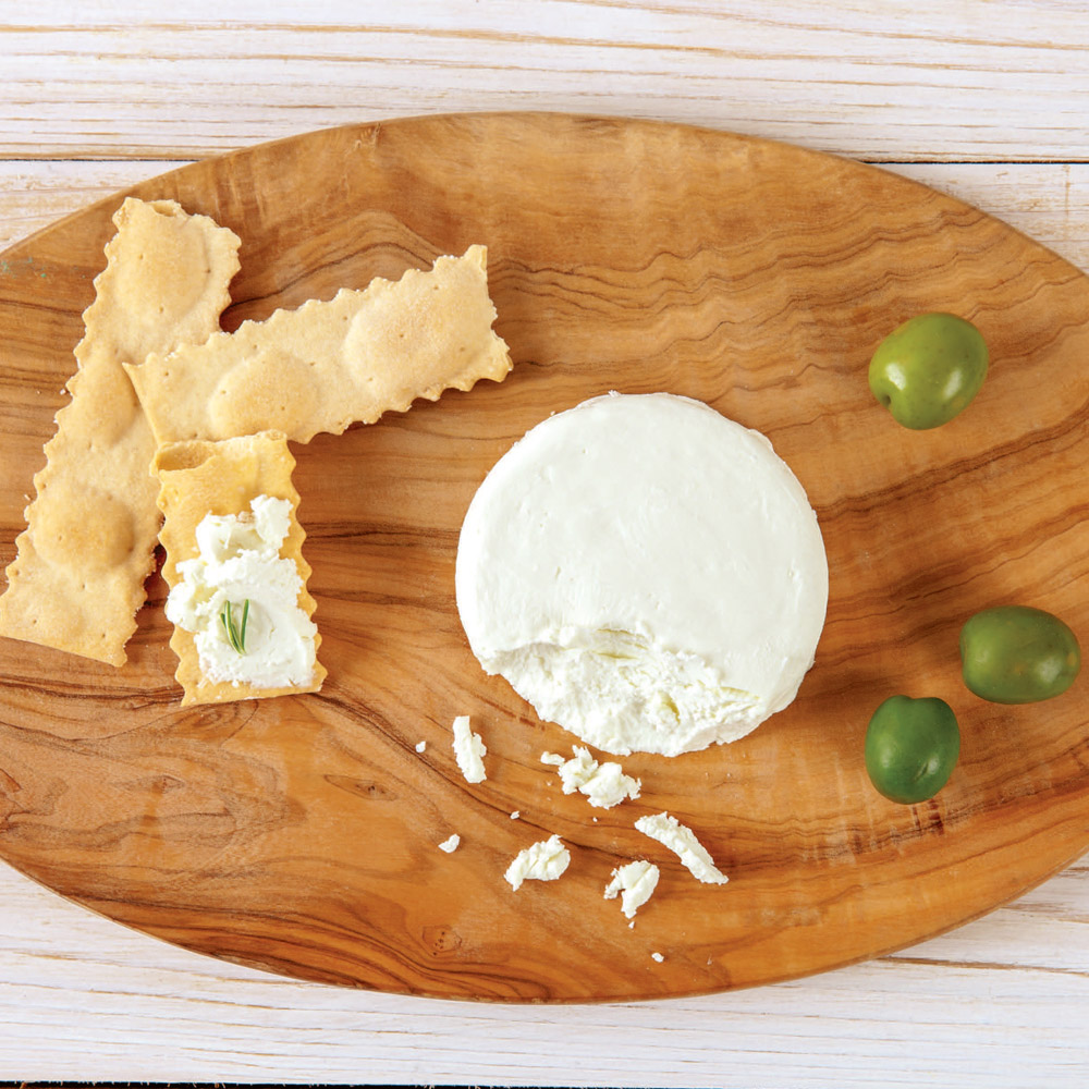Cypress Grove Ms. Natural Chevre on a board between olives and crackers