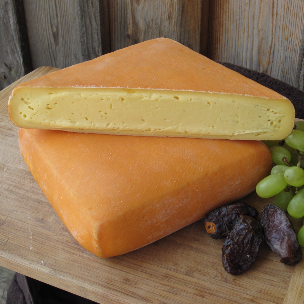 Meadow Creek Dairy Grayson cheese on a board next to a pile of grapes