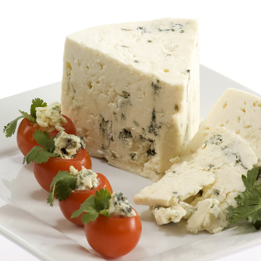 A wedge of Carr Valley Billy Blue cheese on a plate with cherry tomatoes stuffed with blue cheese