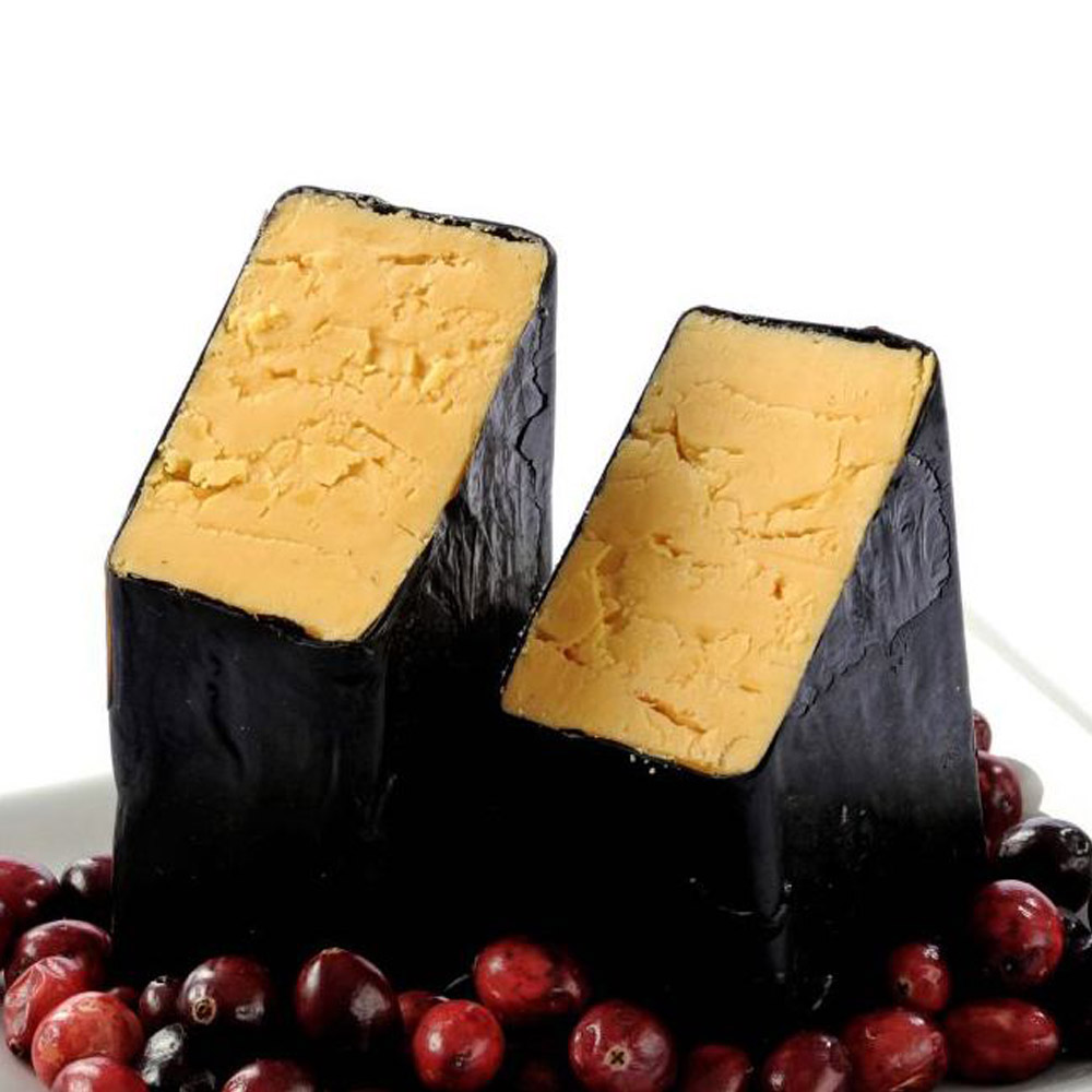 A loaf of Carr Valley 8 Year Aged Cheddar cut in half surrounded by cranberries