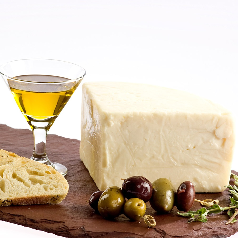 A wedge of Gran Canaria cheese on a slate board with some olives, bread and a glass of olive oil