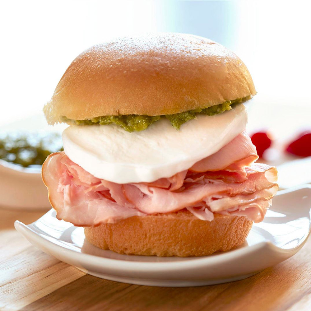 A sandwich with ham and mozzarella on a hamburger bun
