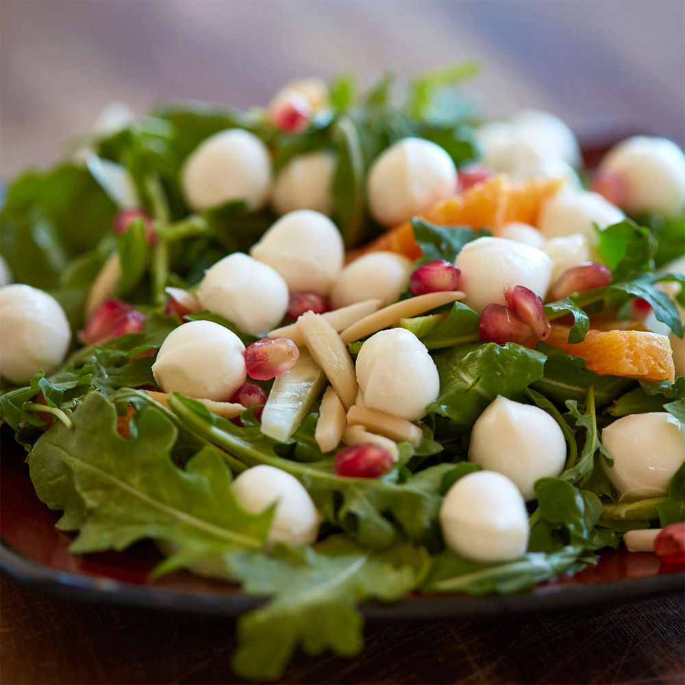 A close-up of a salad topped with fresh mozzarella pearls