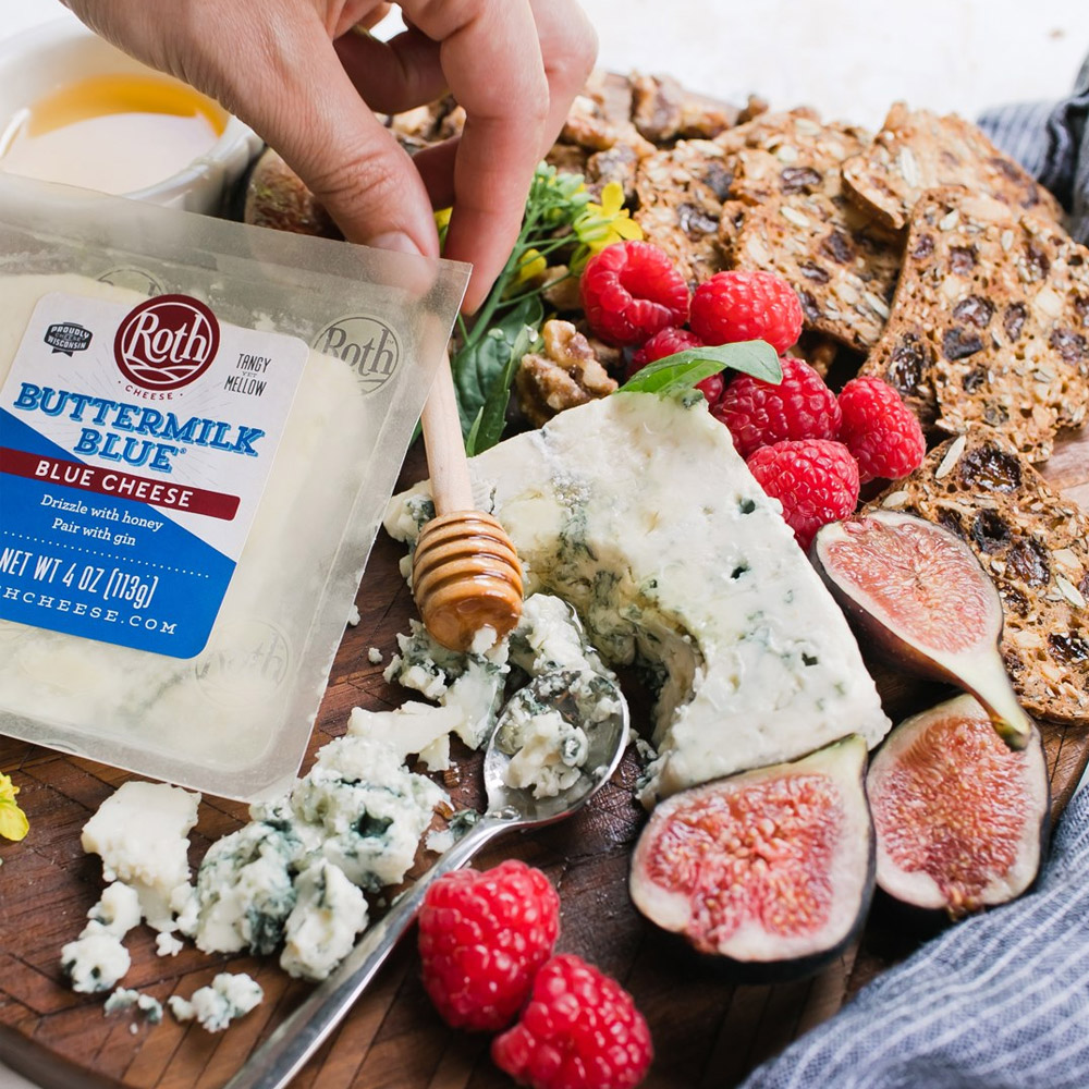 A package of Buttermilk Blue cheese on a cheese board with figs and crackers