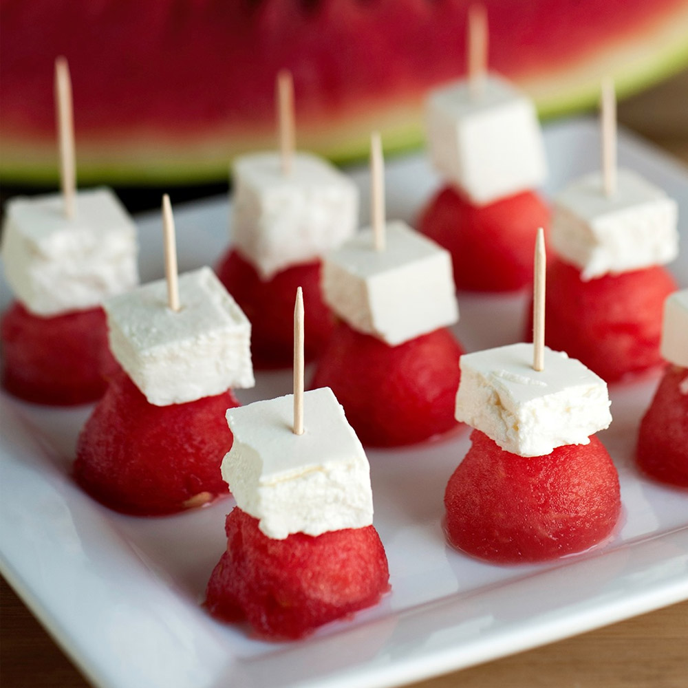A plate of watermelon and feta appetizers on toothpicks