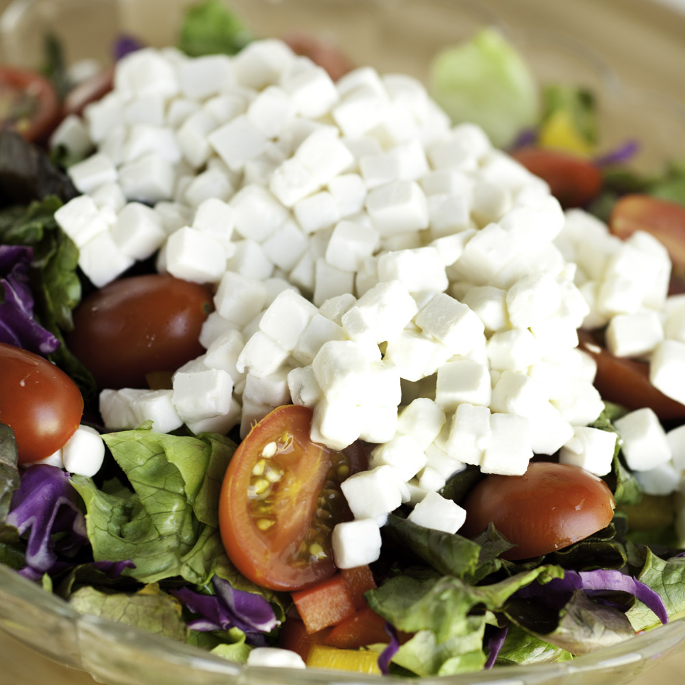 A close-up of a salad topped with a pile of feta cubes