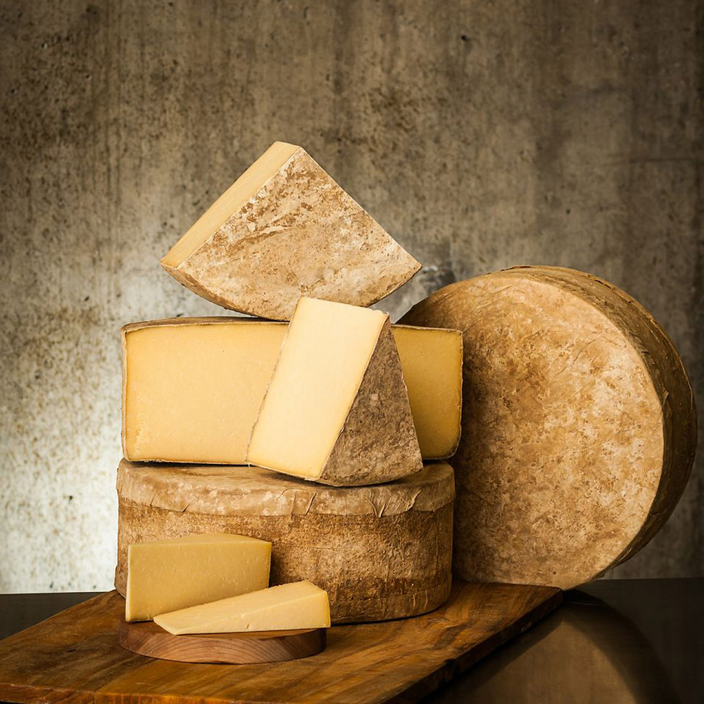 A stack of all different sized cuts of Cabot Clothbound Cheddar cheese