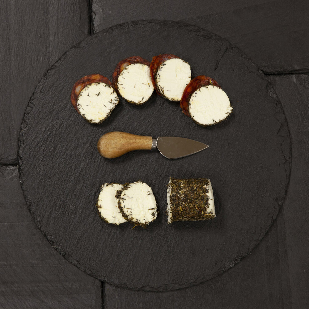 A ssliced log of Old Chatham Creamery garlic and herb chevre on a slate board with slices of pepperoni