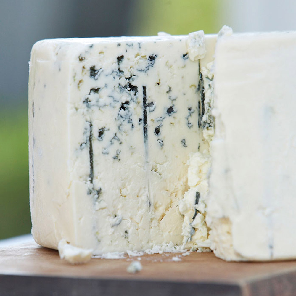 Cut wheel of blue cheese on a wood surface