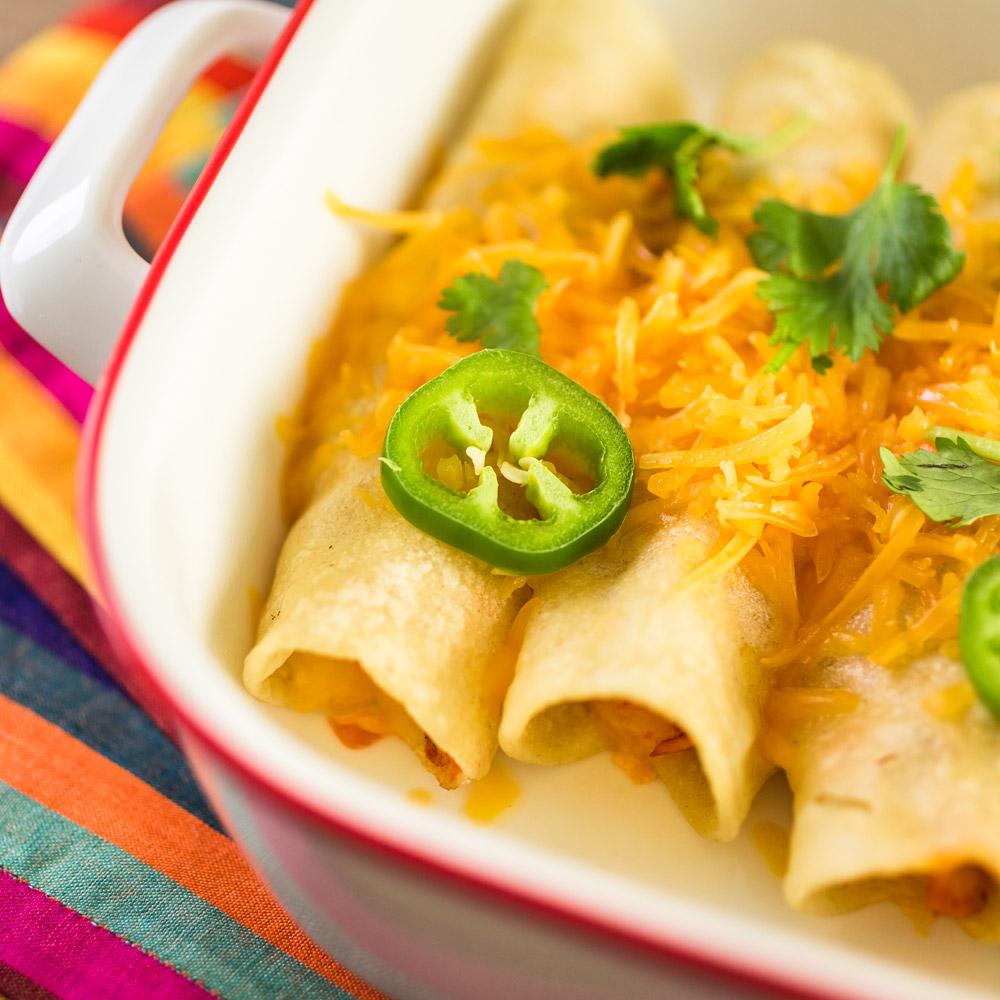 A close-up of cheesy enchaladas topped with jalapenos
