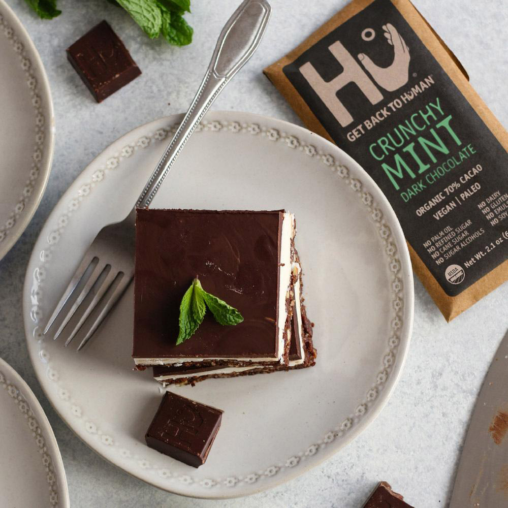 A Hu Crunchy Mint Organic Dark Chocolate Bar next to a plate with a fork and a chocolate mint dessert