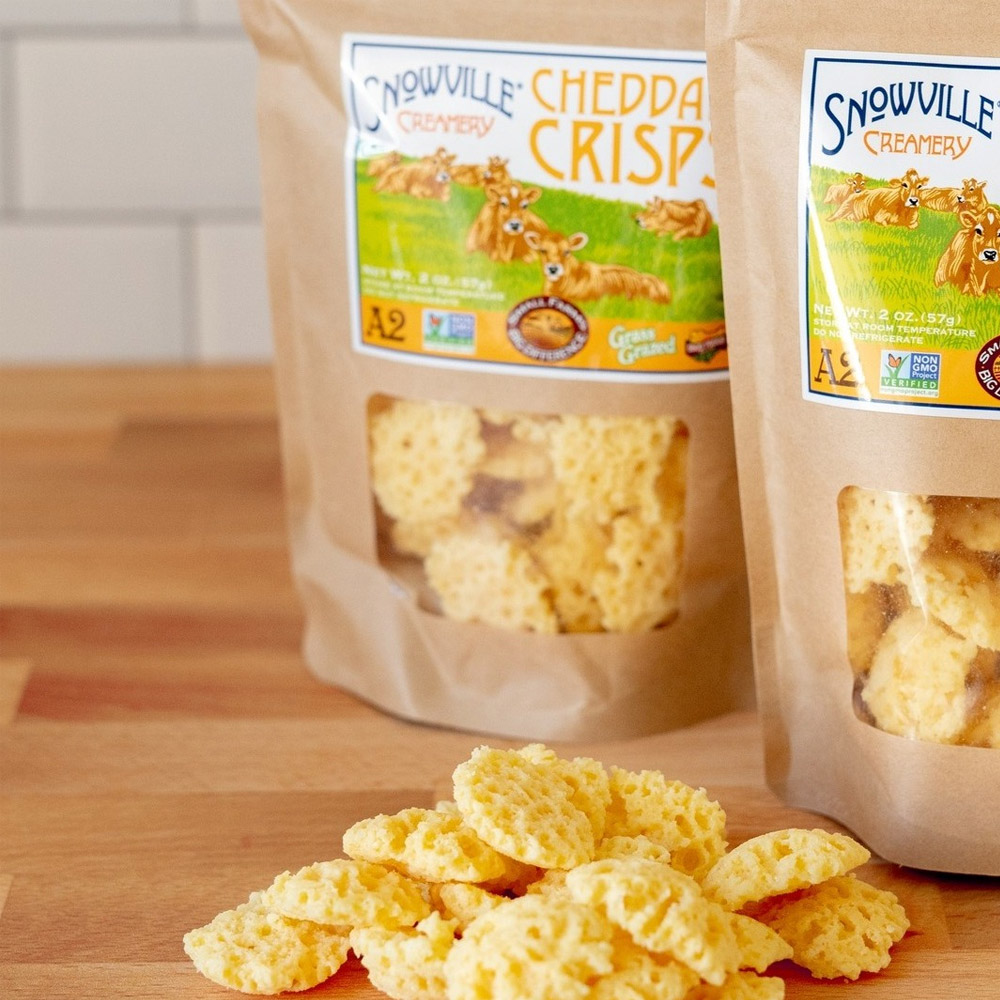 Two bags of cheddar cheese crisps next to a pile of cheese crisps