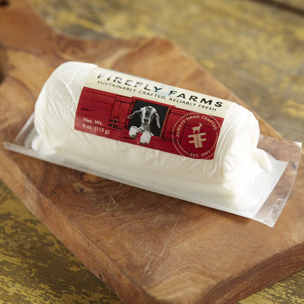 A log of Firefly Farms fresh goat cheese in its packaging on a wood board