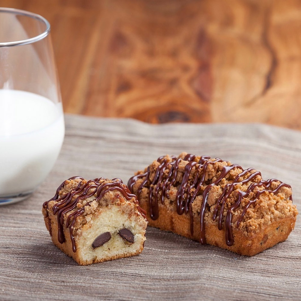 A pastry with chocolate batons next to a glass of milk