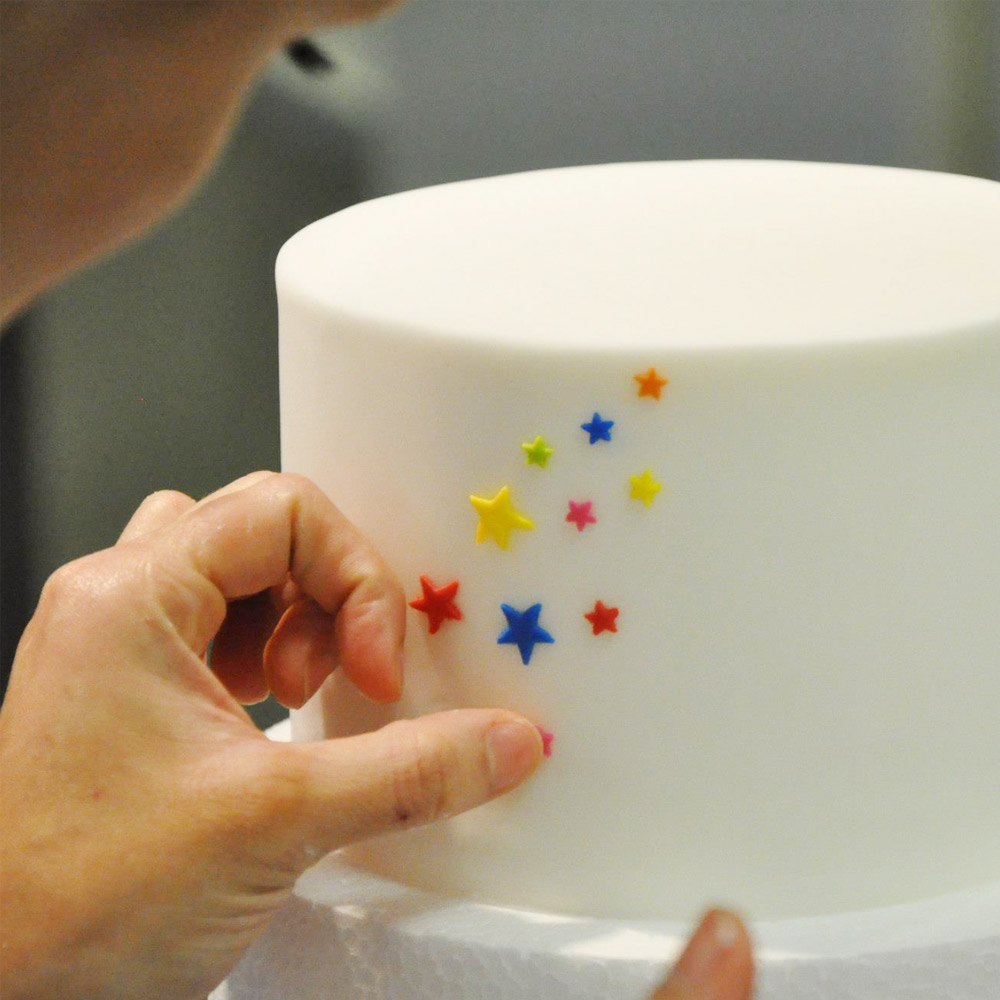 A cake being decorated with Carma Massa Ticino Tropic White Icing
