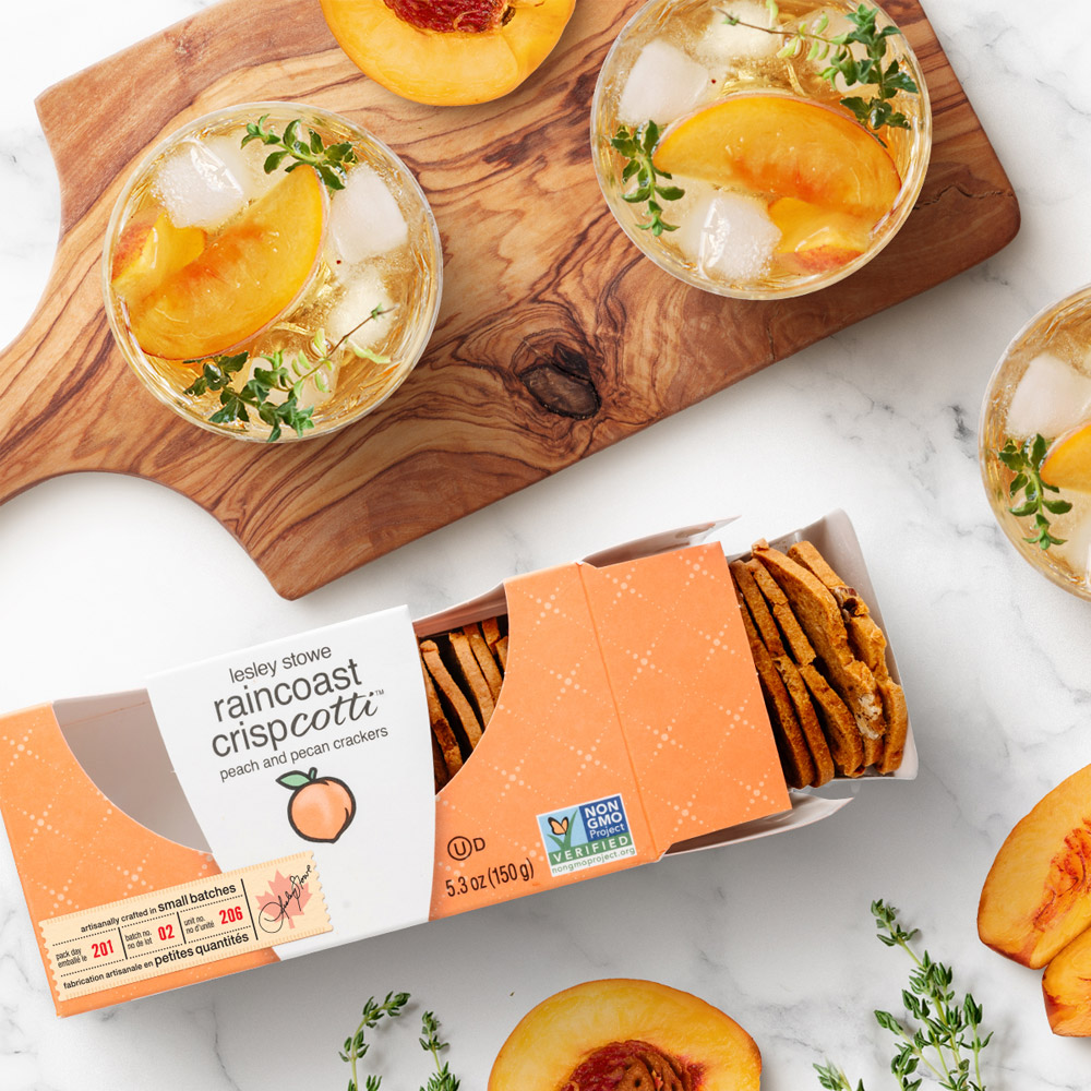 A box of Lesley Stowe Peach Pecan Crispcotti next to drinks topped with peaches