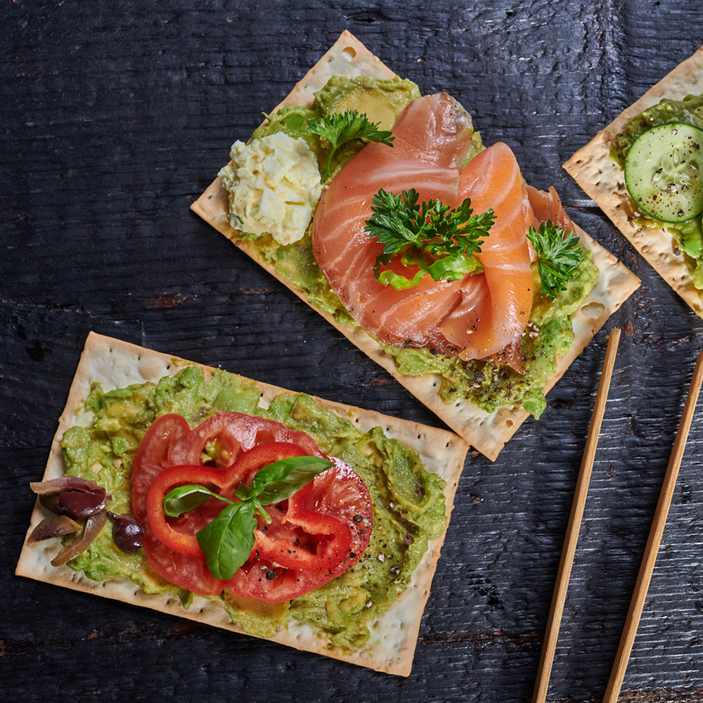 Flatbread crackers shown with a few different topping ideas on top of a slate board