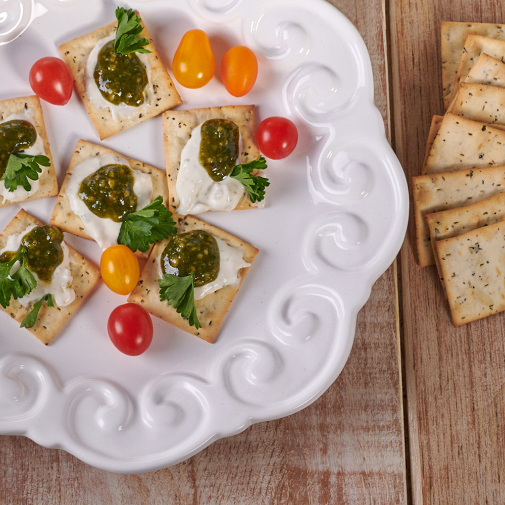 A plate with crackers that have different kids of toppings on them