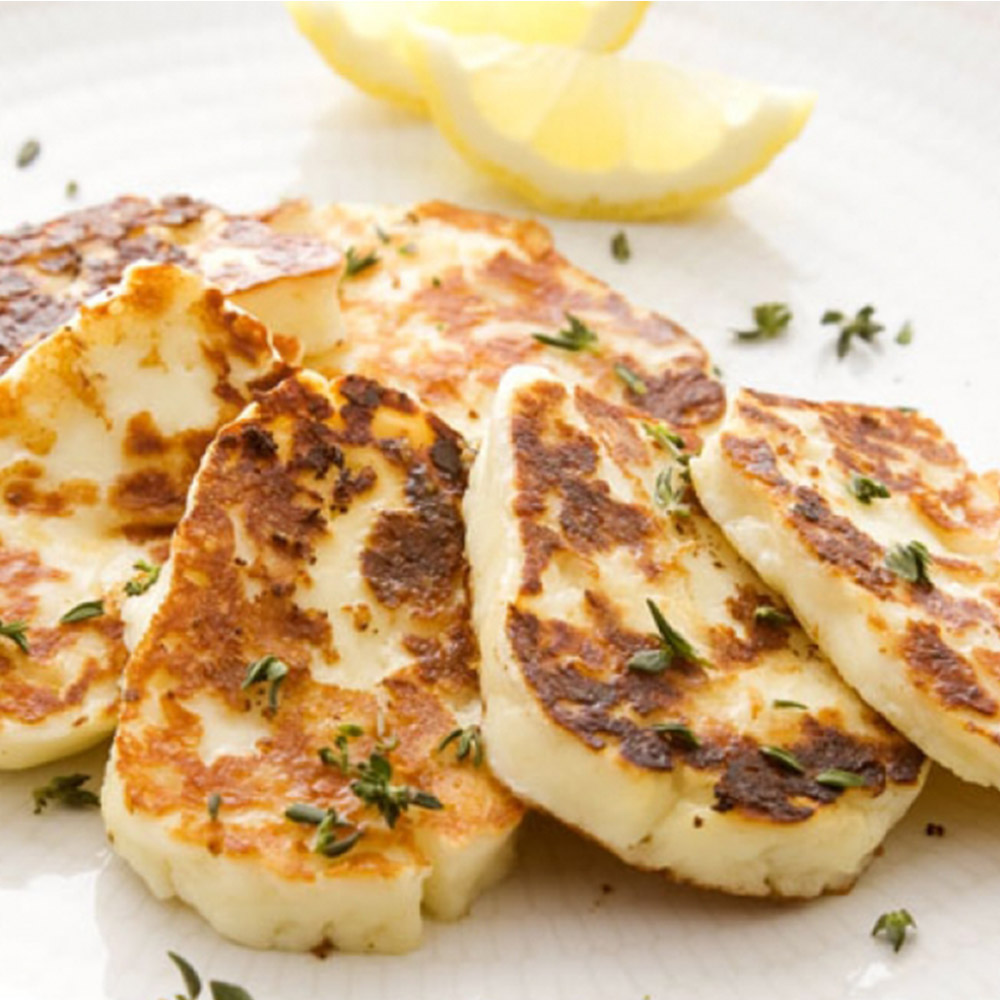 Sliced of grilled halloumi cheese next to lemon wedges