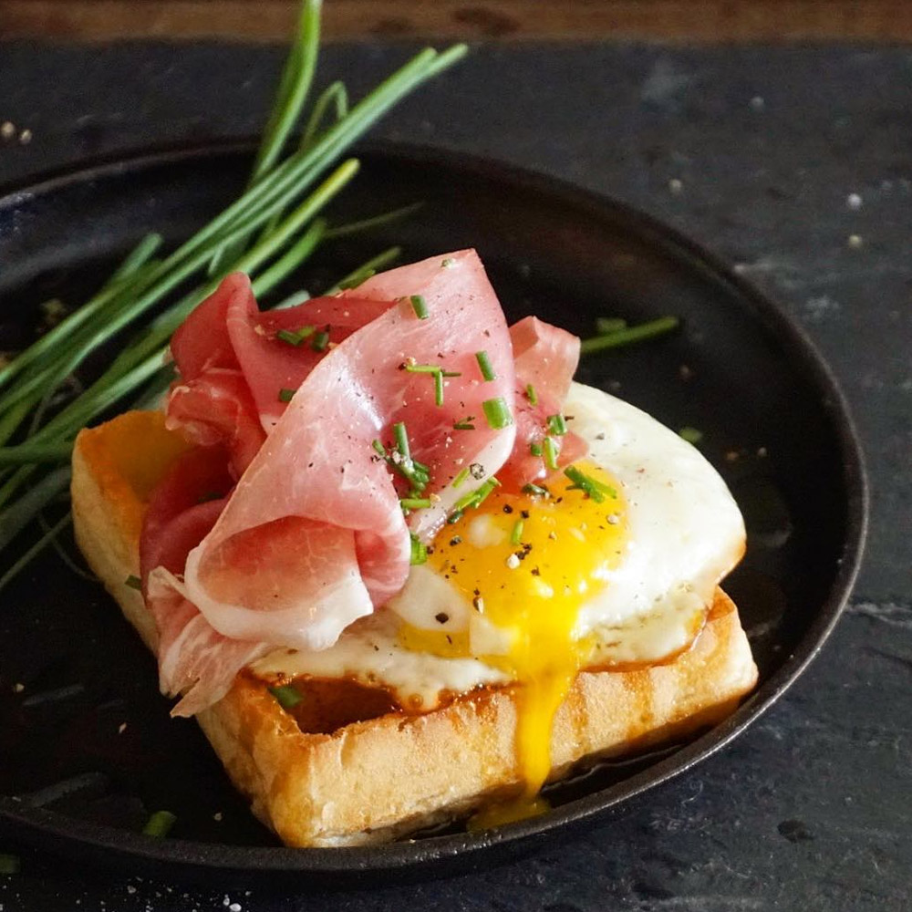 Prosciutto on top of a fried egg on a thick piece of toast