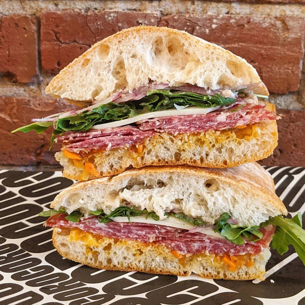 A salami sandwish with a brick background