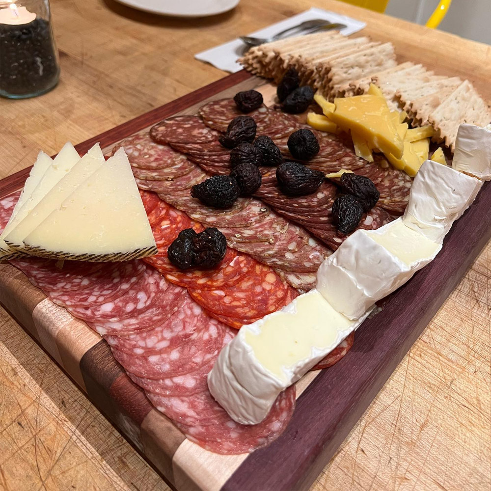 A charcuterie board with five types of salami, crackers and cheese on a table
