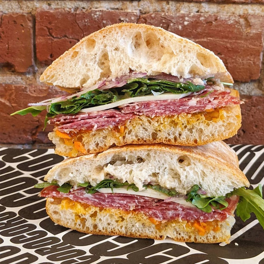 A salami sandwish with a brick background