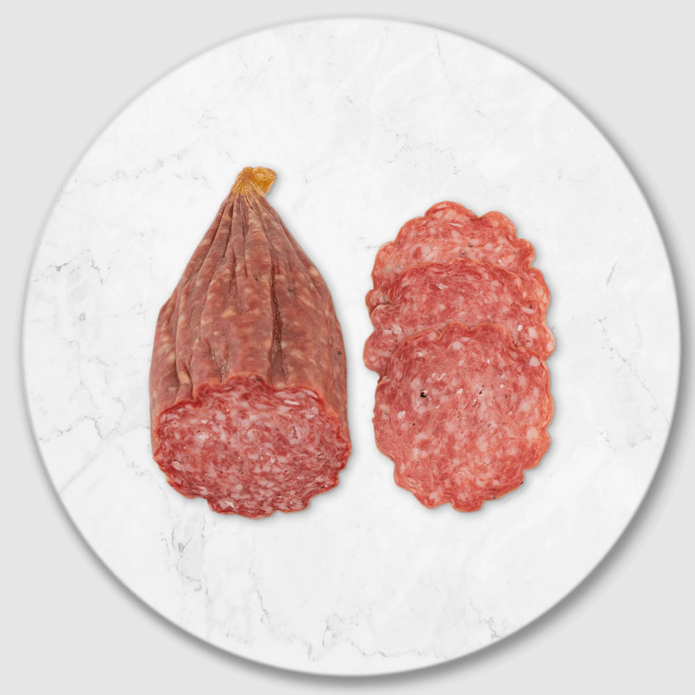 A portion of a salami stick next to slices of salami on a marble board