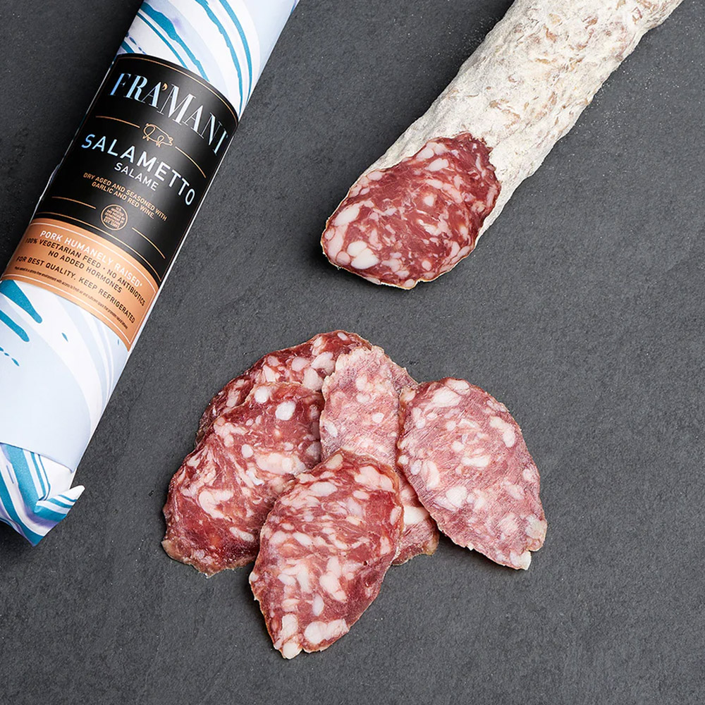fra'mani salametto dry salame in paper wrap next to slices of salami and an unwrapped salami chub