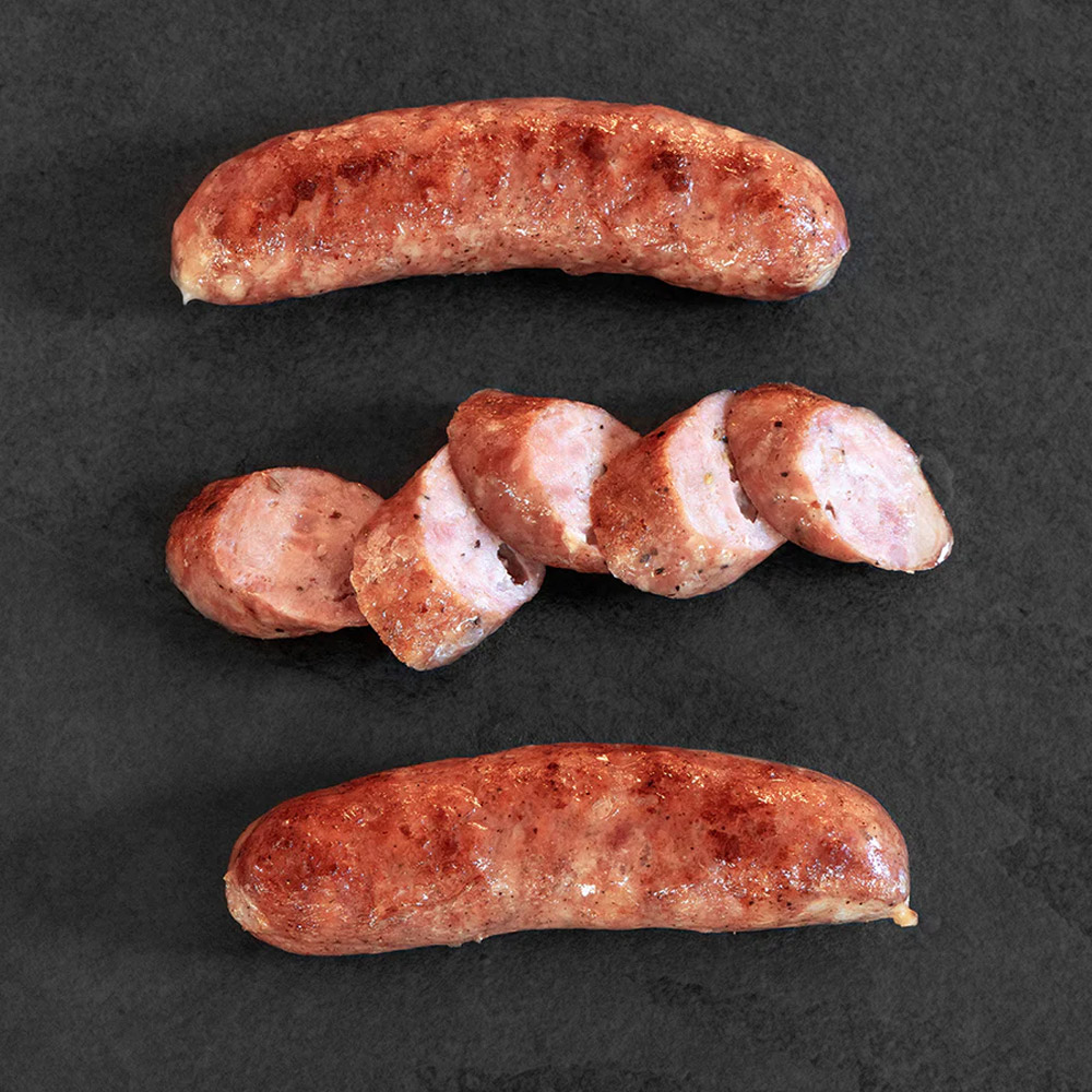 Three cooked sausages in a row with the middle sausage cut in pieces