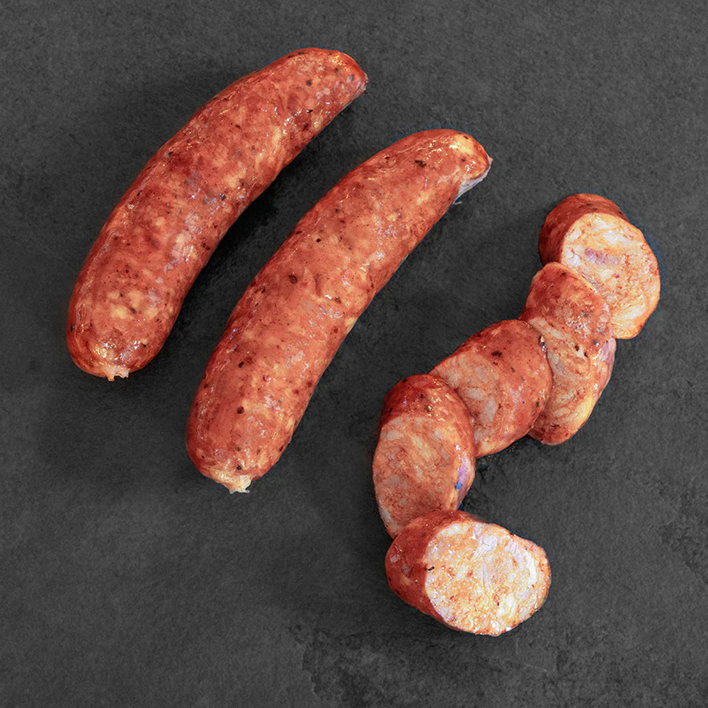 Three cooked sausages in a row with the last sausage cut in pieces