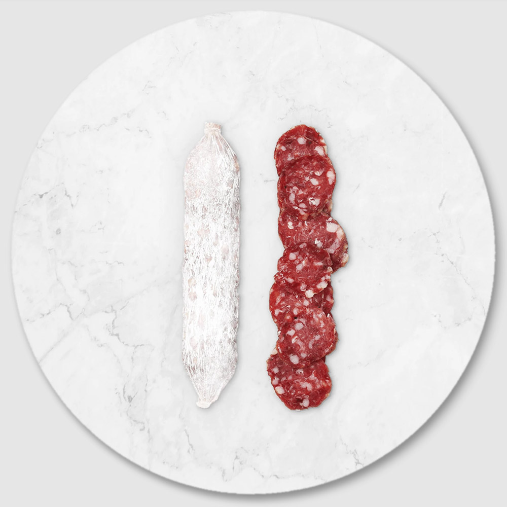 A salami chub next to slices of salami on a marble board