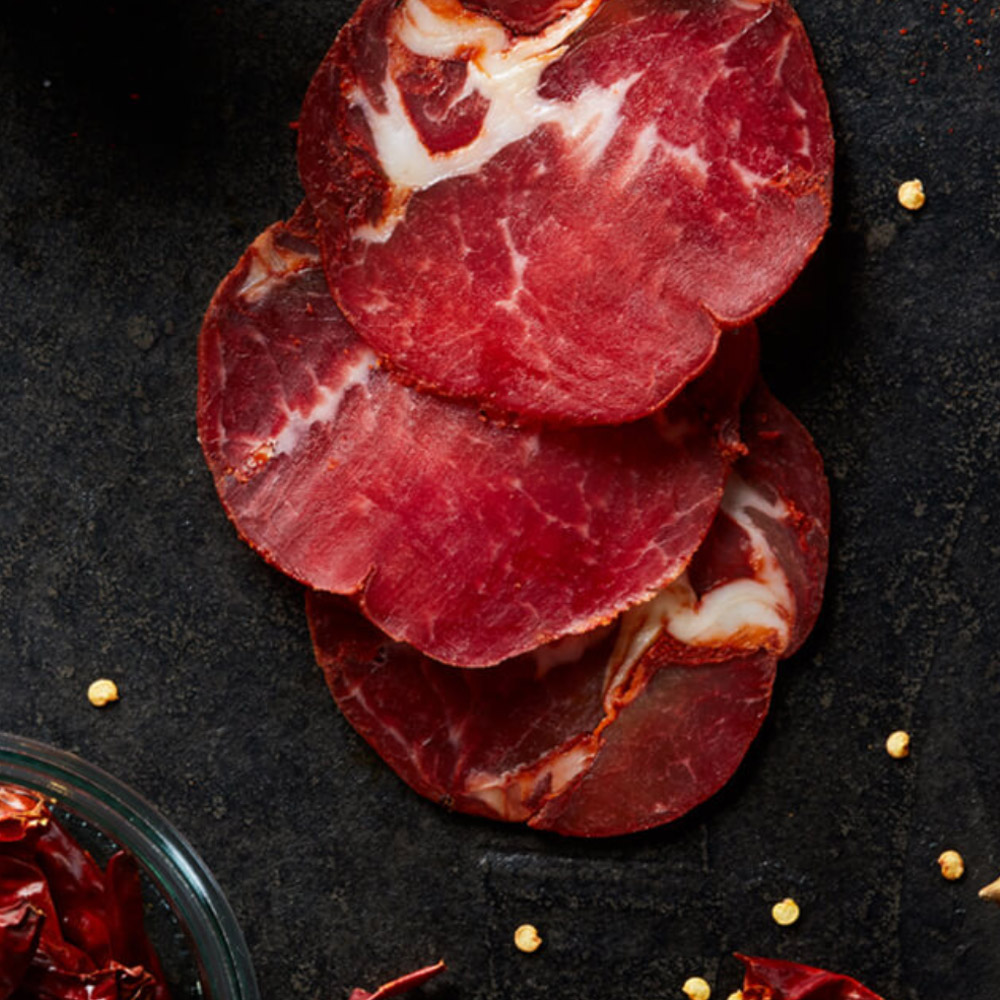 Slices of hot coppa on a dark background