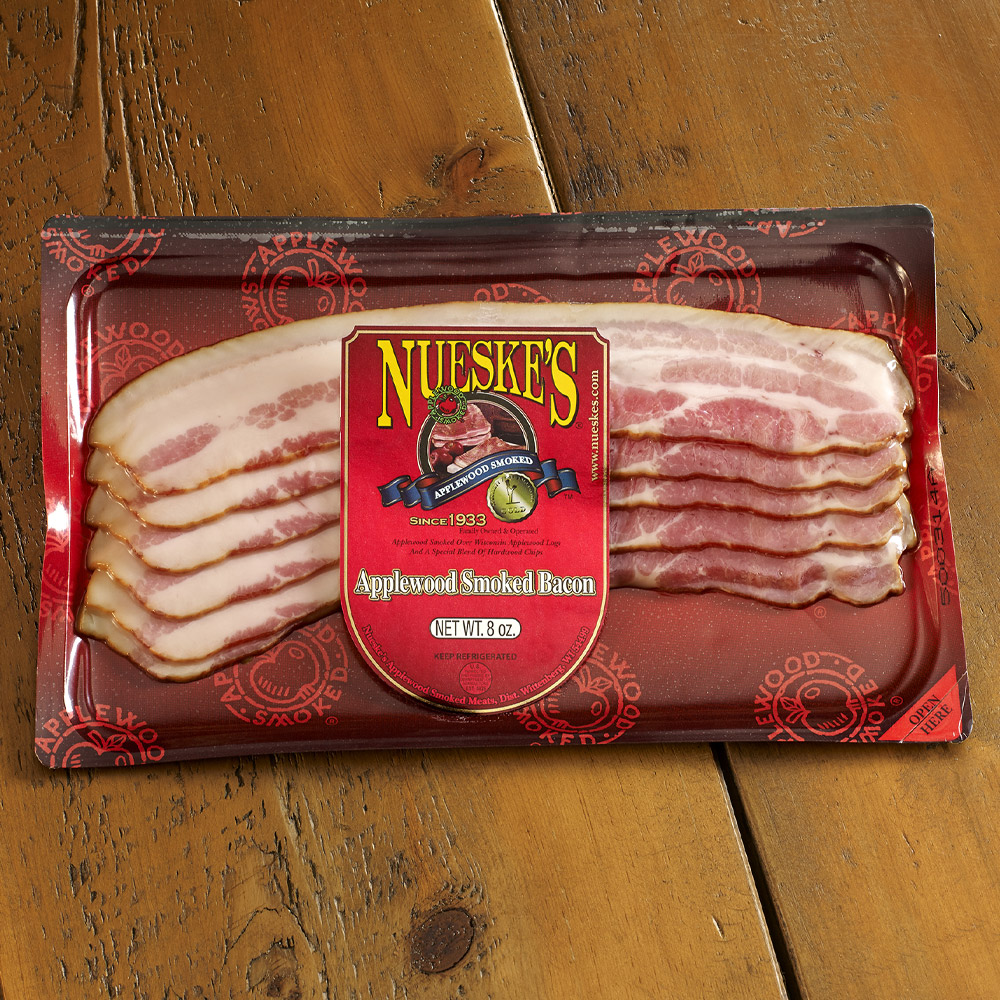 nueske's applewood smoked sliced bacon in plastic packaging on wooden table