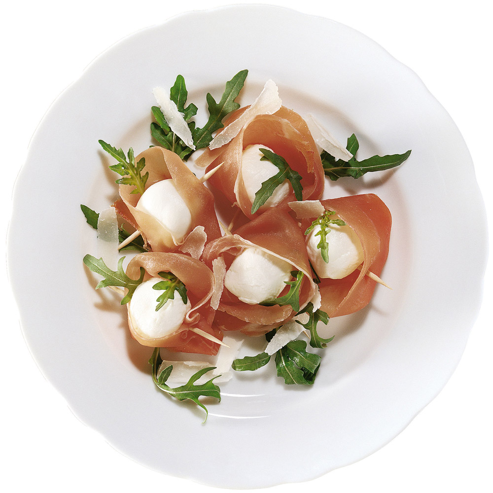 A plate filled with speck and mozzarella balls topped with greens